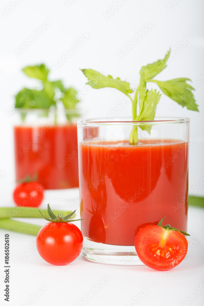 Glass of tomato juice with cherry tomatoes and celery leaves on white background, vertical Glass of tomato juice with cherry tomatoes and celery leaves on white background, vertical