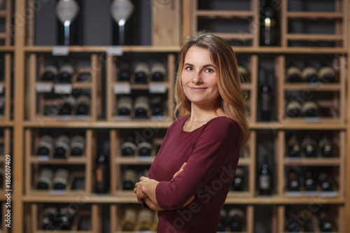 Attractive woman sommelier in wine cellar background