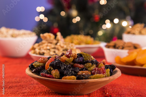 Raisins into a bowl on rustic old wooden table with christmas background. photo