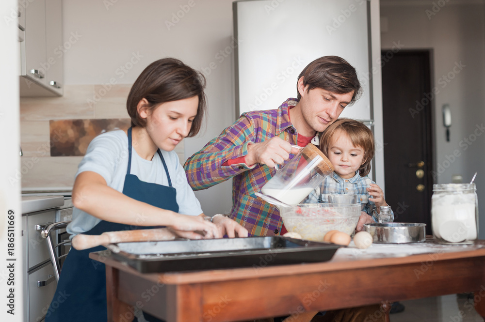 Fototapeta premium beautiful young family preparing dough for homemade cookies