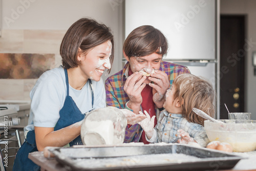 adorable young family having fun with flour at kitchen while baking