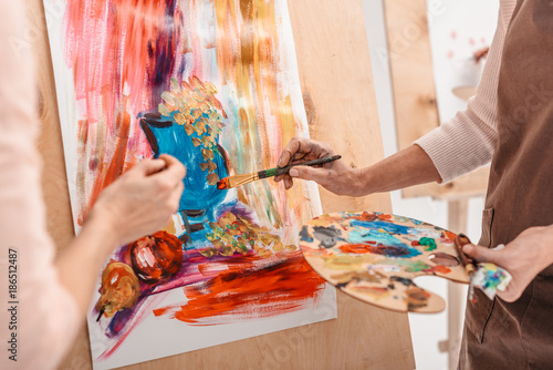 cropped shot of artists with palette painting still life on easel