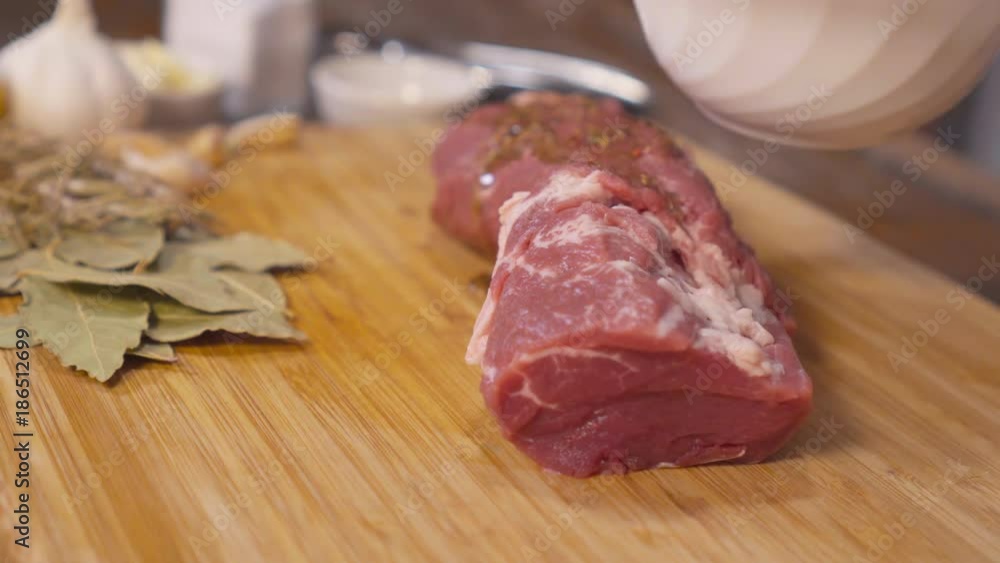Female hands sprinkle spices and pour the meat with olive oil. Meat in the home kitchen. Making pork meat Female hands sprinkle spices and pour the meat with olive oil. Meat in the home kitchen. Making pork meat