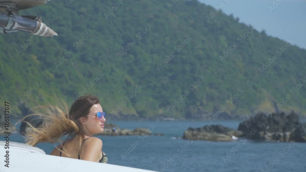 A beautiful girl in sunglasses is sailing on a yacht and looking at the sea. The wind blows her hair. A beautiful girl in sunglasses is sailing on a yacht and looking at the sea. The wind blows her hair.