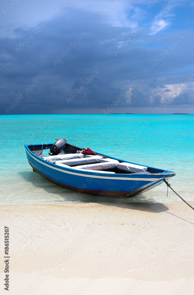 Blue Maldivian boat on the white sand beach