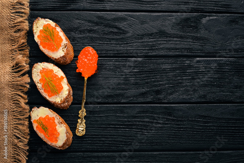 Sandwich with red caviar and butter. On a wooden background. Top view. Free space for text.