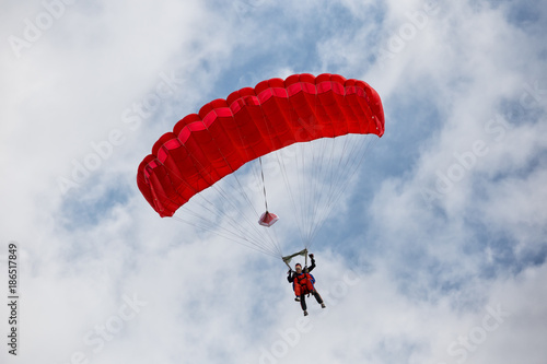 Parachuter descending with a red parachute photo