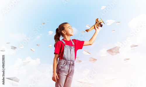 Concept of careless happy childhood with girl throwing retro plane © adam121