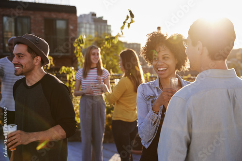 Happy friends at a rooftop party backlit by sunlight photo