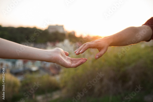 Hands of man and woman reaching to each other
