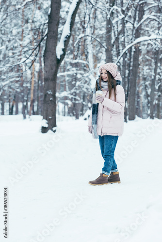 attractive woman in winter clothing with coffee to go on winter day in park