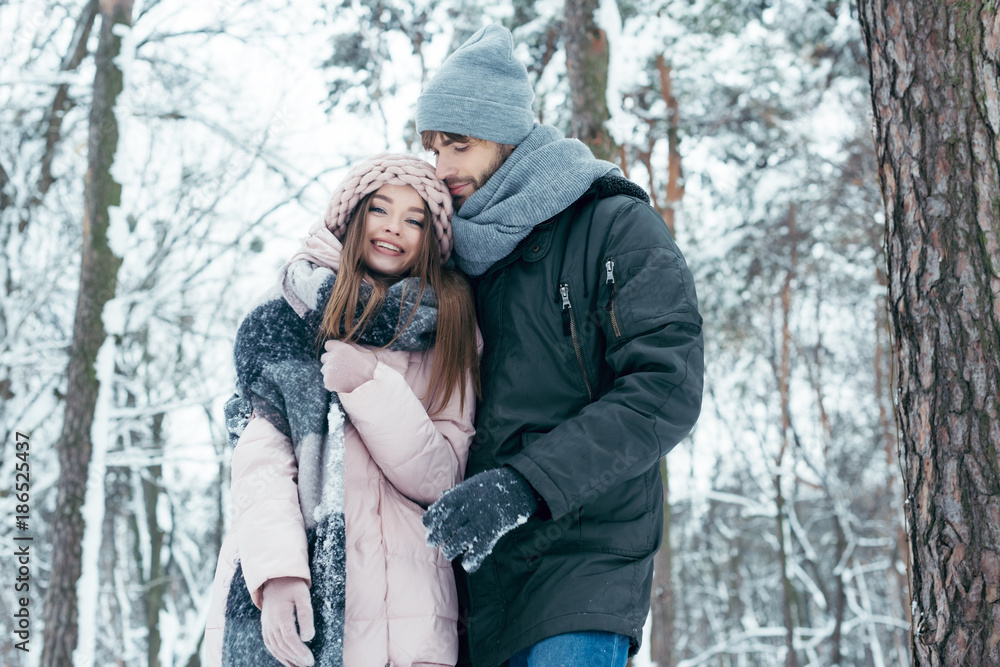 young man hugging girlfriend in winter forest young man hugging girlfriend in winter forest