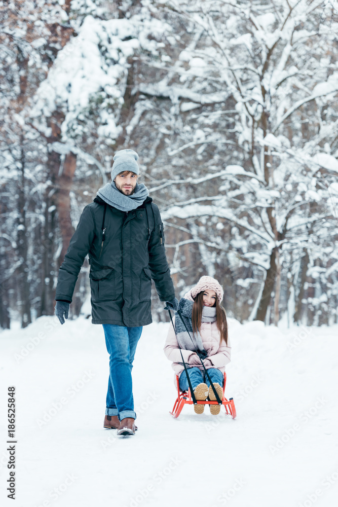 young couple sledging together on winter day in park