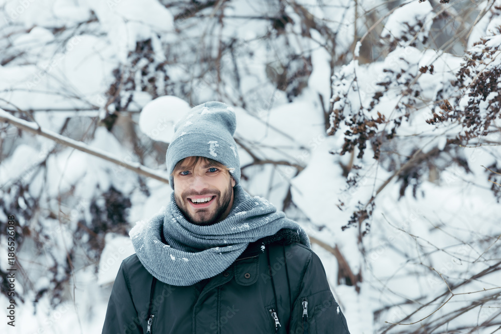 portrait of cheerful young man looking at camera on winter day in park portrait of cheerful young man looking at camera on winter day in park
