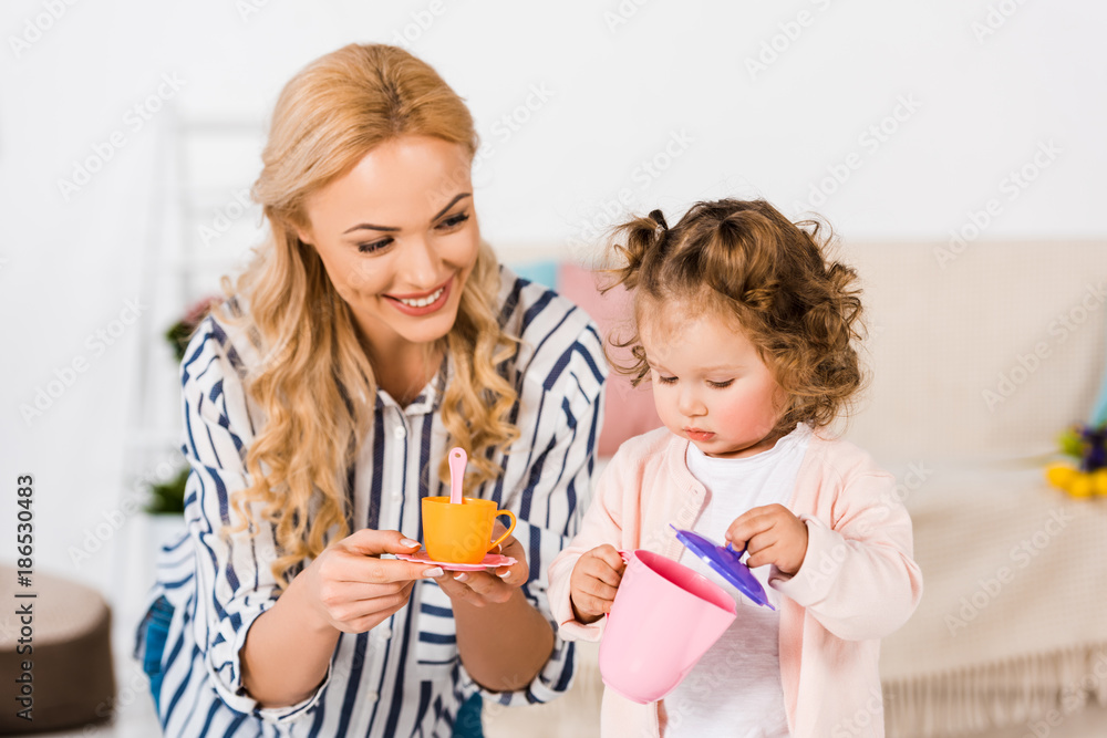 smiling mother and daughter playing with plastic cups smiling mother and daughter playing with plastic cups