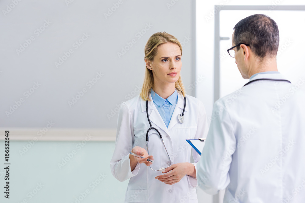 two doctors in white coats discussing diagnosis in clinic two doctors in white coats discussing diagnosis in clinic