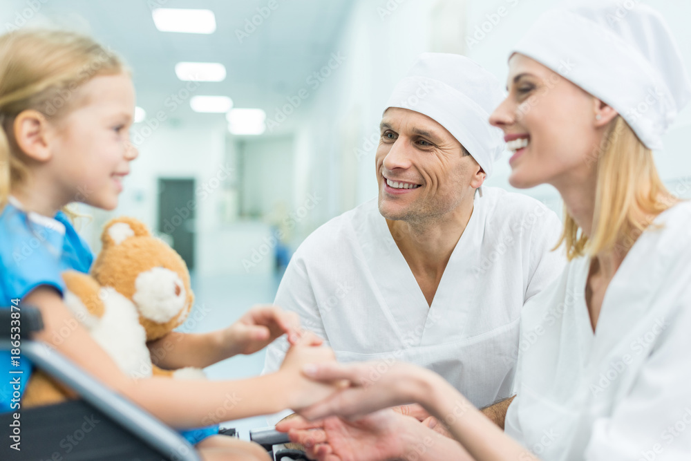smiling doctors and patient on wheelchair holding hands smiling doctors and patient on wheelchair holding hands