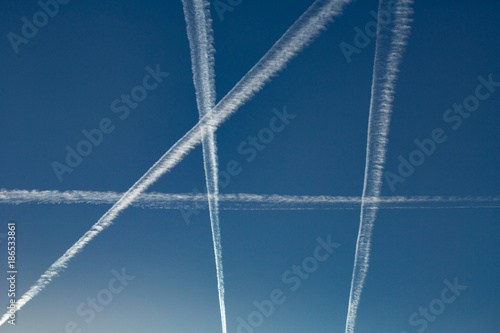 contrails crossing over deep blue sky