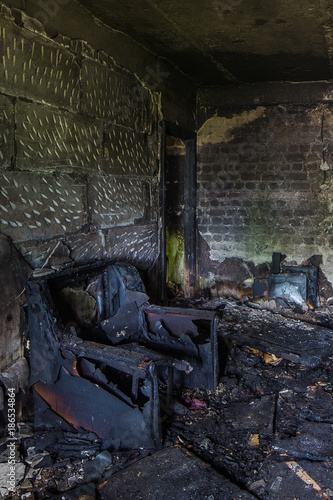 Burnt apartment house interior. Burned chair, charred walls
