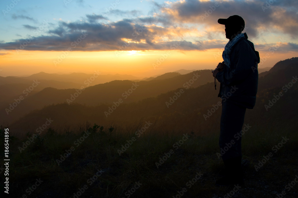A trourist man stading on peak of mountains and enjoy to see beautiful landscape view of sunset, hiking tourist adventure on vacation on mountains