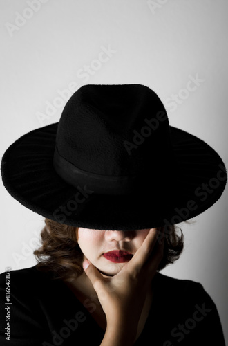 Beautiful young woman wearing black dress  black hat and red lips in the dark concept  Concept   dark  halloween  mysterious  depressed