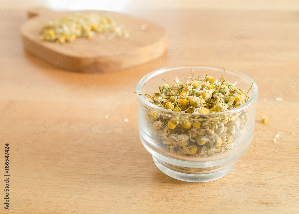 Dried Camomile in cup glass on wooden table Dried Camomile in cup glass on wooden table