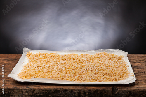 Raw handmade italian pasta maccheroncini on a wooden table. Black background photo