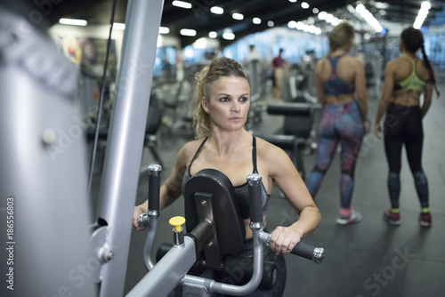 Mature woman training shoulders and back at gym machines