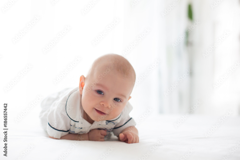 Cute little four month old baby boy, playing at home in bed Cute little four month old baby boy, playing at home in bed