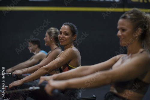 Women training rowing in gym with exercises machines and pull rope