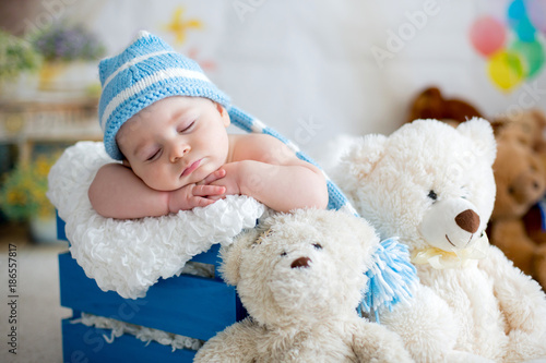 Little baby boy with knitted hat, sleeping with cute teddy bear