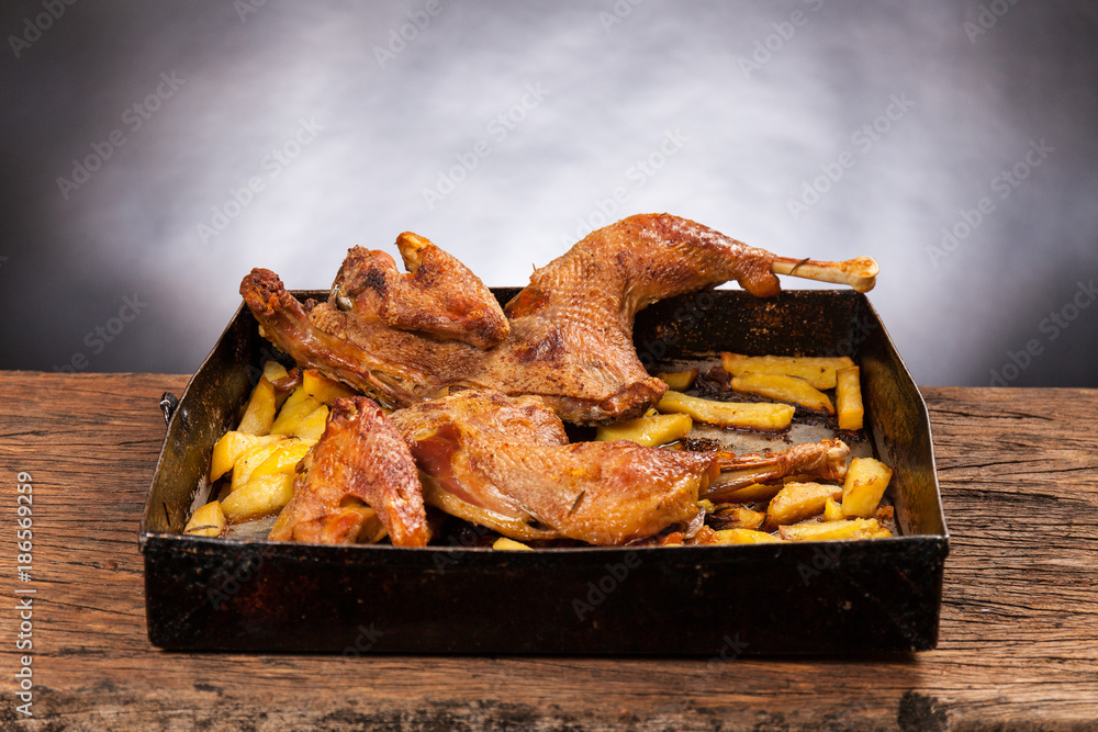 Roast cut chicken with potatoes on a wooden table. Black background. Porn  food Stock Photo | Adobe Stock