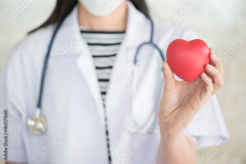 profressional woman doctor with green stethoscope and red heart in her hand photo