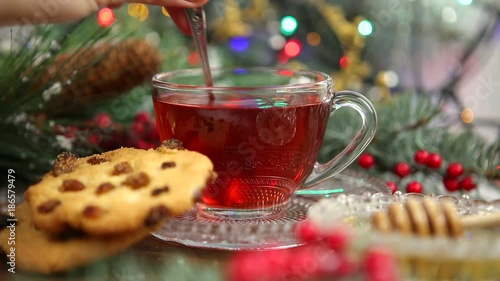 a cup of tea with honey and cookies, a branch of a Christmas tree in the snow, Christmas lights