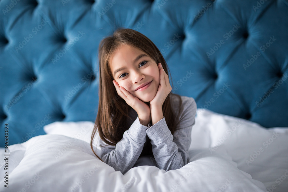 cute smiling little girl woke up in white bed holding pillow cute smiling little girl woke up in white bed holding pillow
