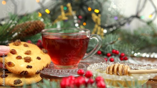 a cup of tea with honey and cookies, a branch of a Christmas tree in the snow, Christmas lights