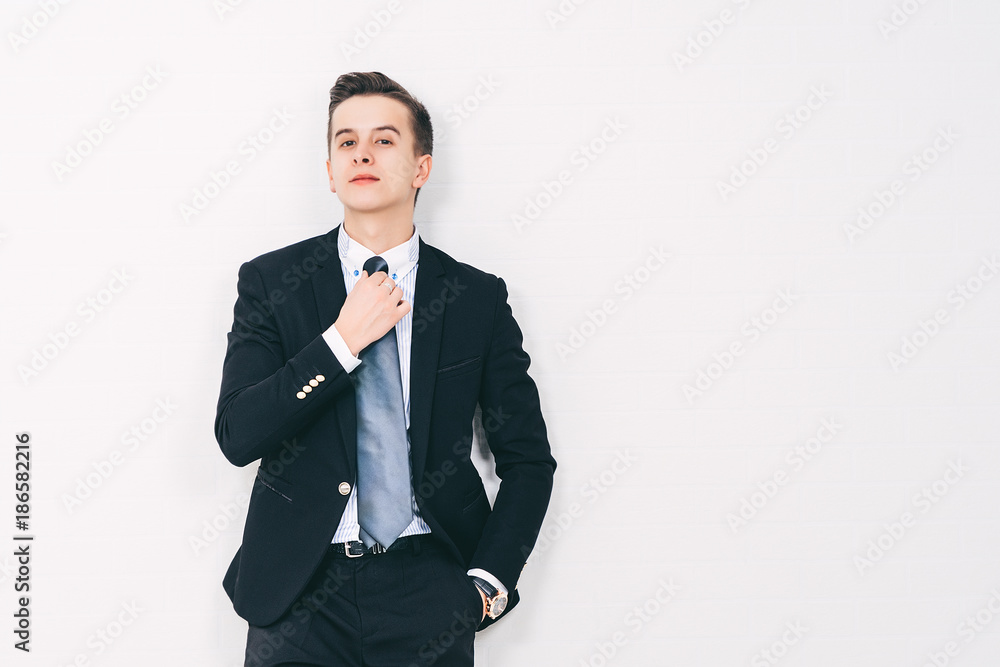 Young business man is standing and leaning on the white wall, copy space, business concept. Young business man is standing and leaning on the white wall, copy space, business concept.