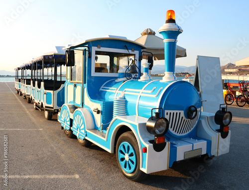 Blue and white tourist excursion locomotive on sea beach in Greece
