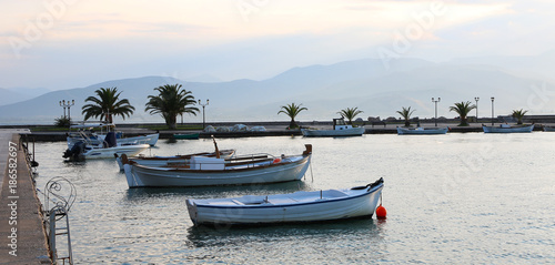 Set of white vintage wood boats on sea with mountain background during sunset