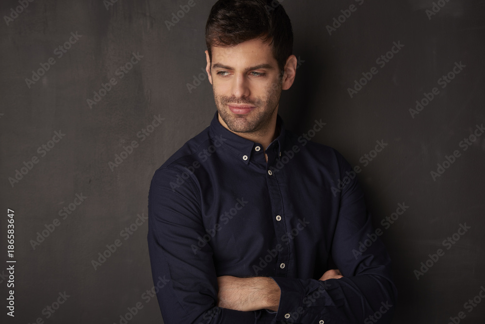 Studio shot of a handsome young man against dark grey background 