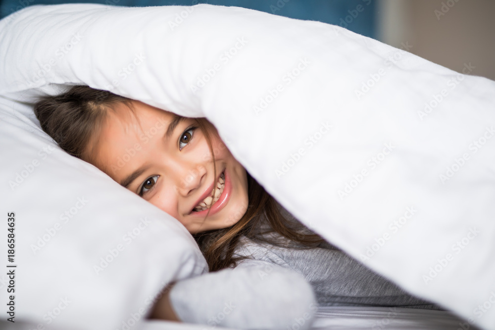 girl lying under a blanket in the bed and smiling at home girl lying under a blanket in the bed and smiling at home