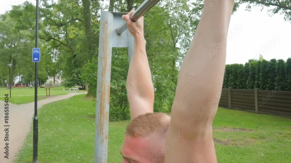 Close up of strong male athlete doing pull-up on horizontal bar outdoors in park Close up of strong male athlete doing pull-up on horizontal bar outdoors in park