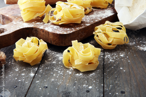 Making homemade pasta linguine on rustic kitchen table with flour, rolling pin and pasta