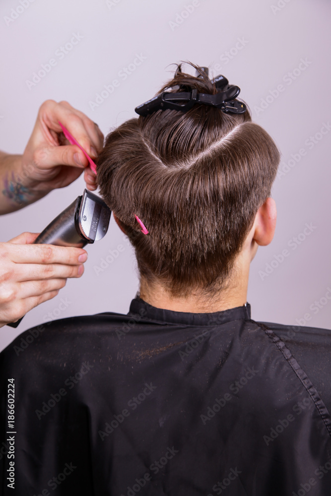 Fototapeta premium The process of male haircuts. A hairdresser is cutting a guy. Barber does a haircut.Hair will be sheared, hair cut. The machine for a hairstyle