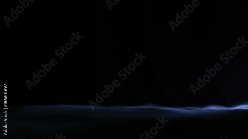 This is a video of dry ice smoke gently swirling over what appears to be a low hillside against a black background. There are no people and there's a lot of space for copy. The smoke was back lit.
