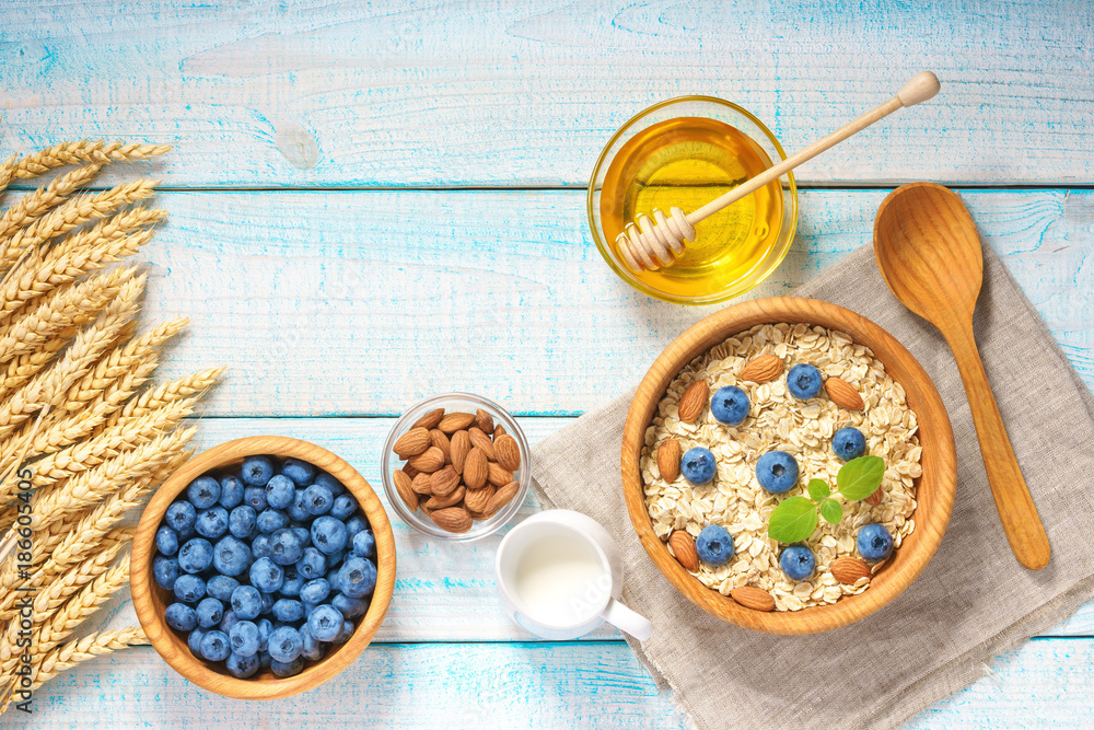 Fototapeta premium Healthy breakfast with oat flakes, natural milk, fresh blueberries. Top view.