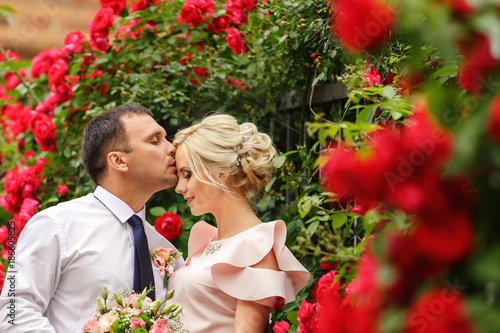 Bild auf Leinwand Caucasian couple in love kissing near red flowers