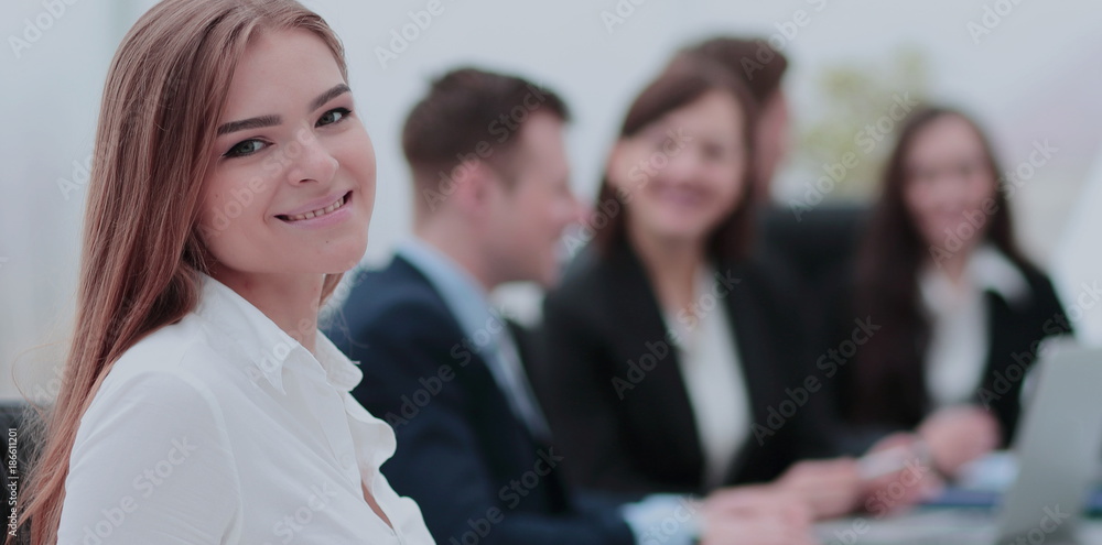 Portrait of a smiling businesswoman sitting at a table with coll Portrait of a smiling businesswoman sitting at a table with coll