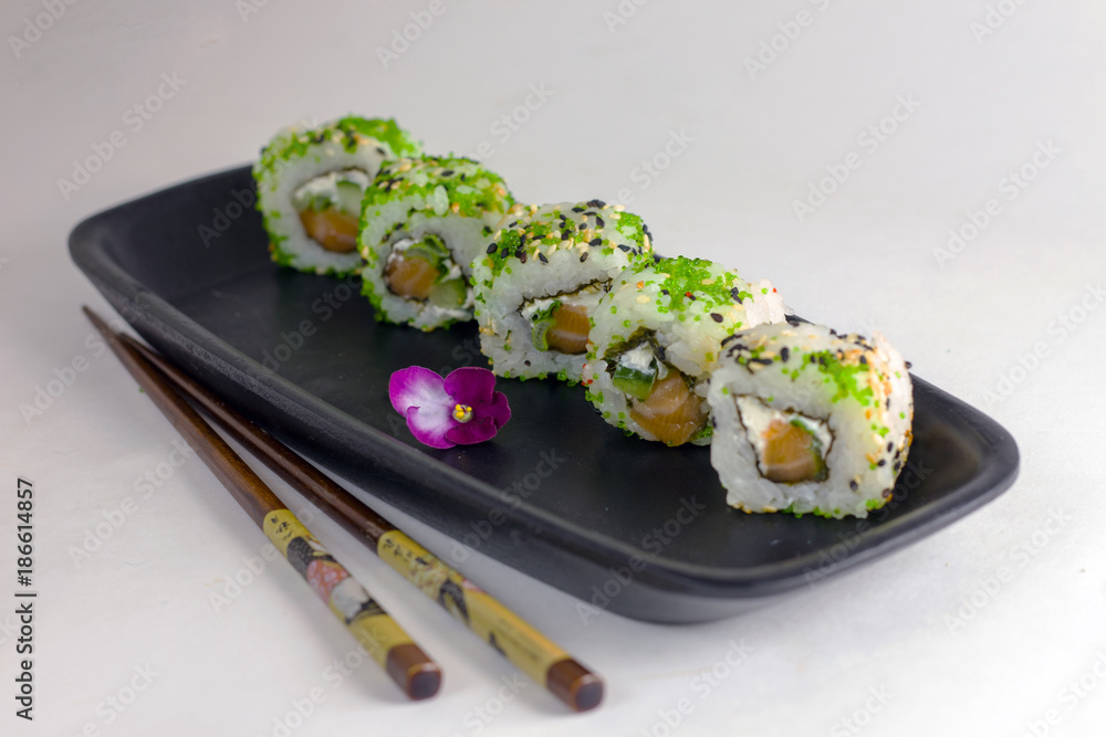 Green sushi rolls on a black rectangular elongated dish with chopsticks Green sushi rolls on a black rectangular elongated dish with chopsticks
