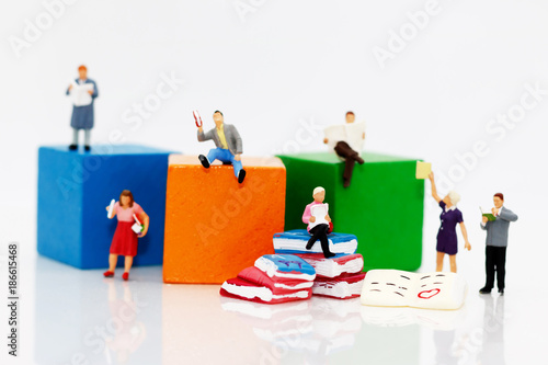 Miniature people reading  book with colorful wooden blocks, education or business concept.
